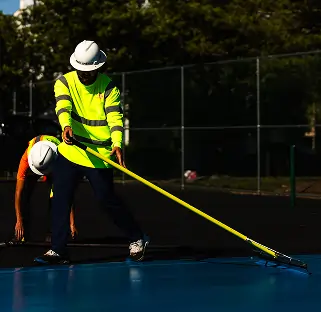 Contractor applying paint to a sports court